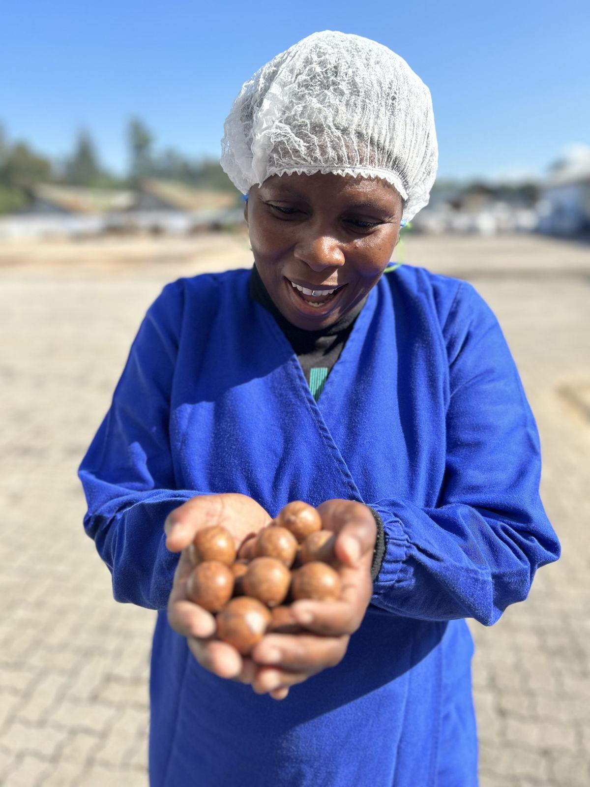 Phumzile, a production supervisor, smiling and holding macadamia nuts in cupped hands
