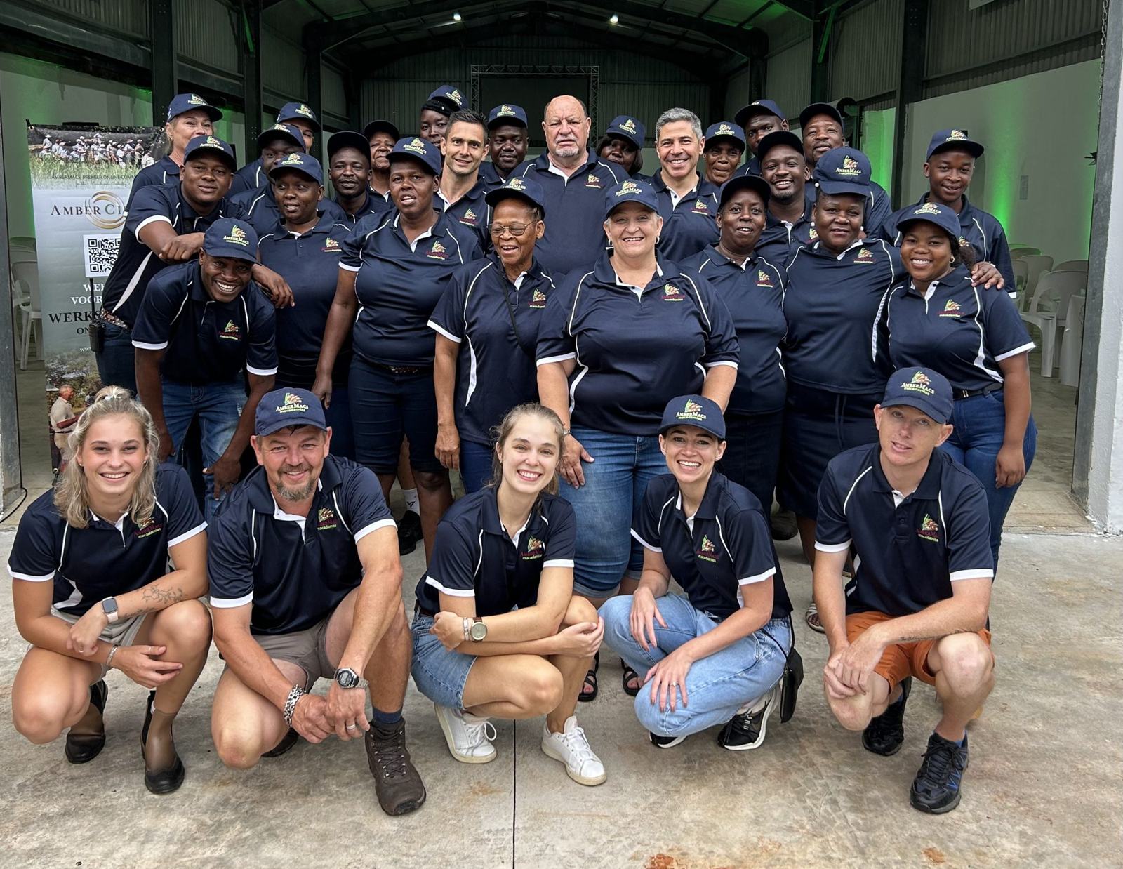 The Amber Macs factory team in matching navy shirts and caps